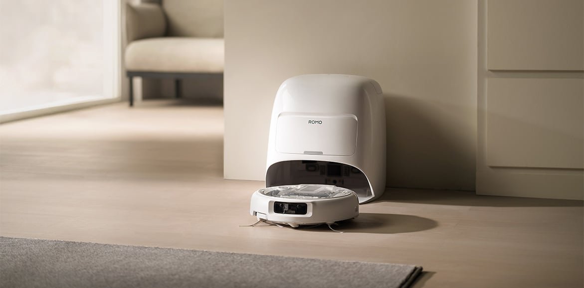 Robot sprzątający DJI ROMO A wyjeżdża ze stacji dokującej w beżowym pokoju